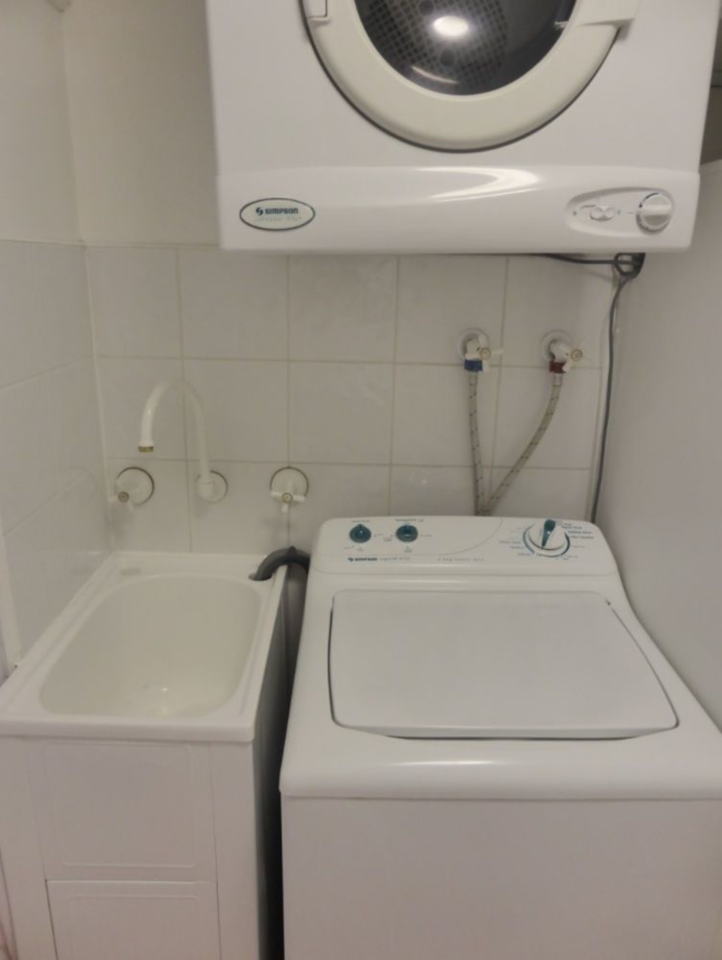 Un espacio pequeño para la lavandería con lavadora y lavabo.