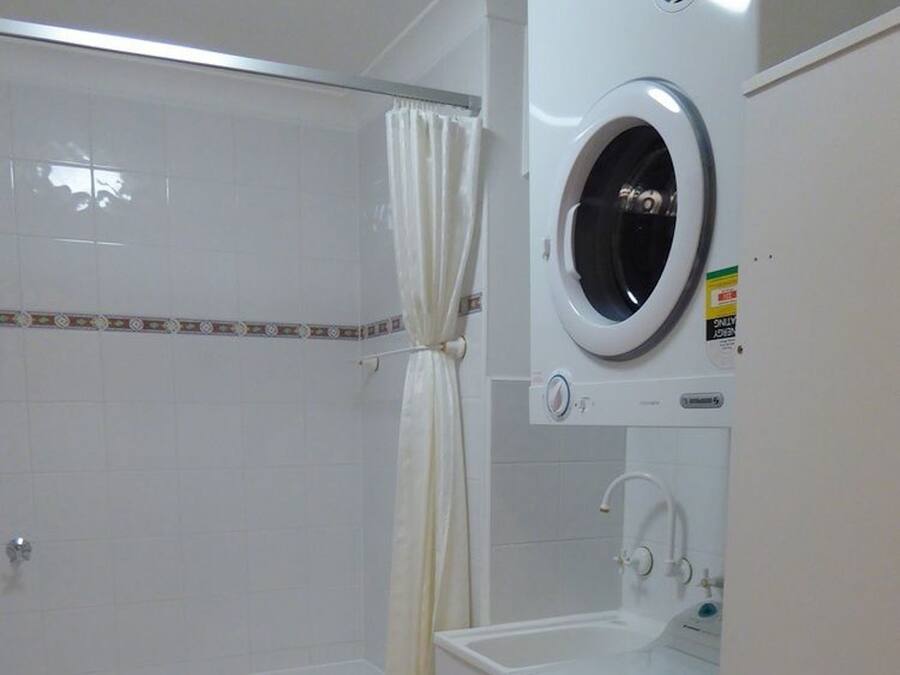 A bathroom with a bathtub, a shower, a washing machine, and a sink.