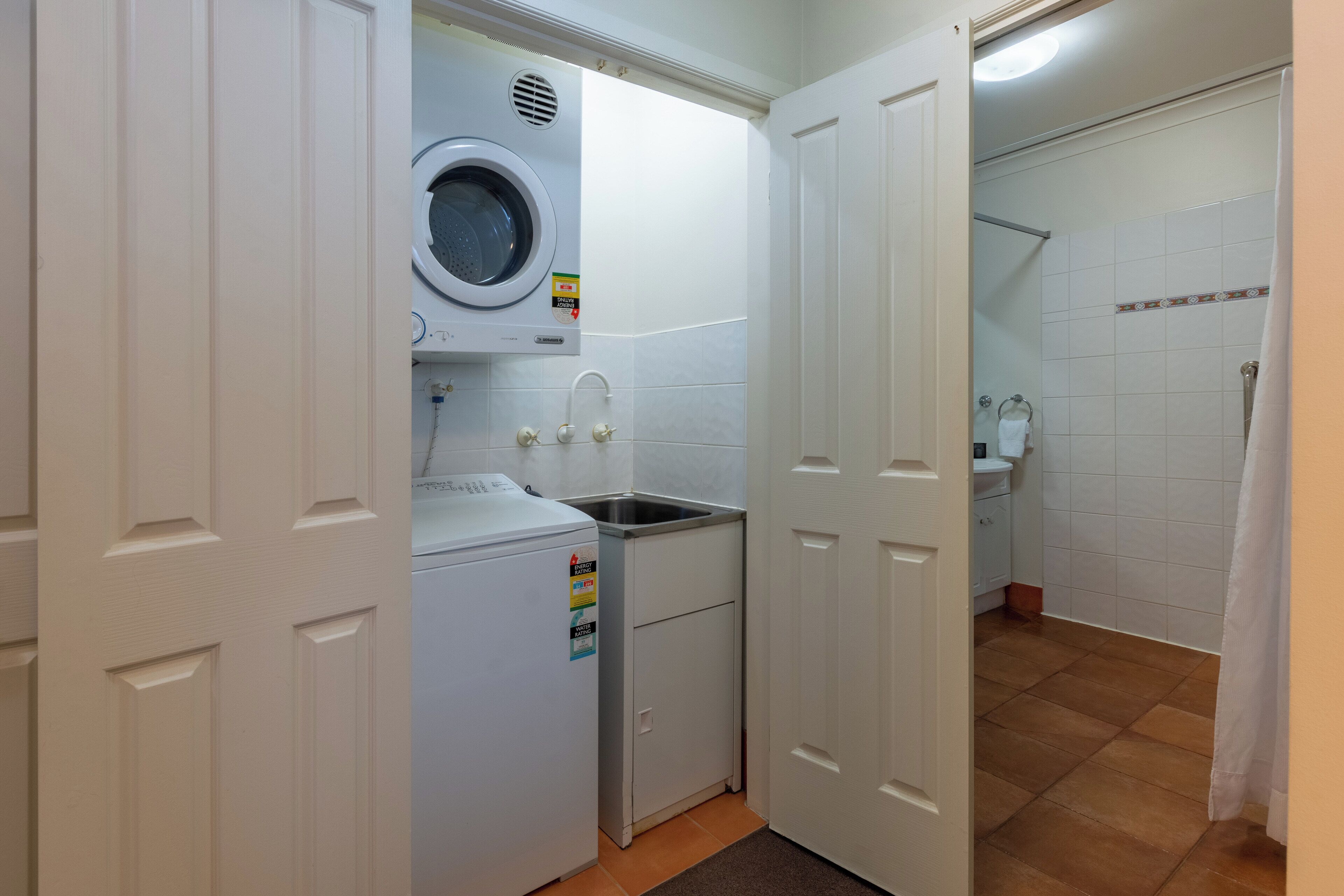 A compact laundry area with a washing machine, a sink, and a small cabinet.