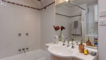 A bathroom with a bathtub, a sink, and a mirror.