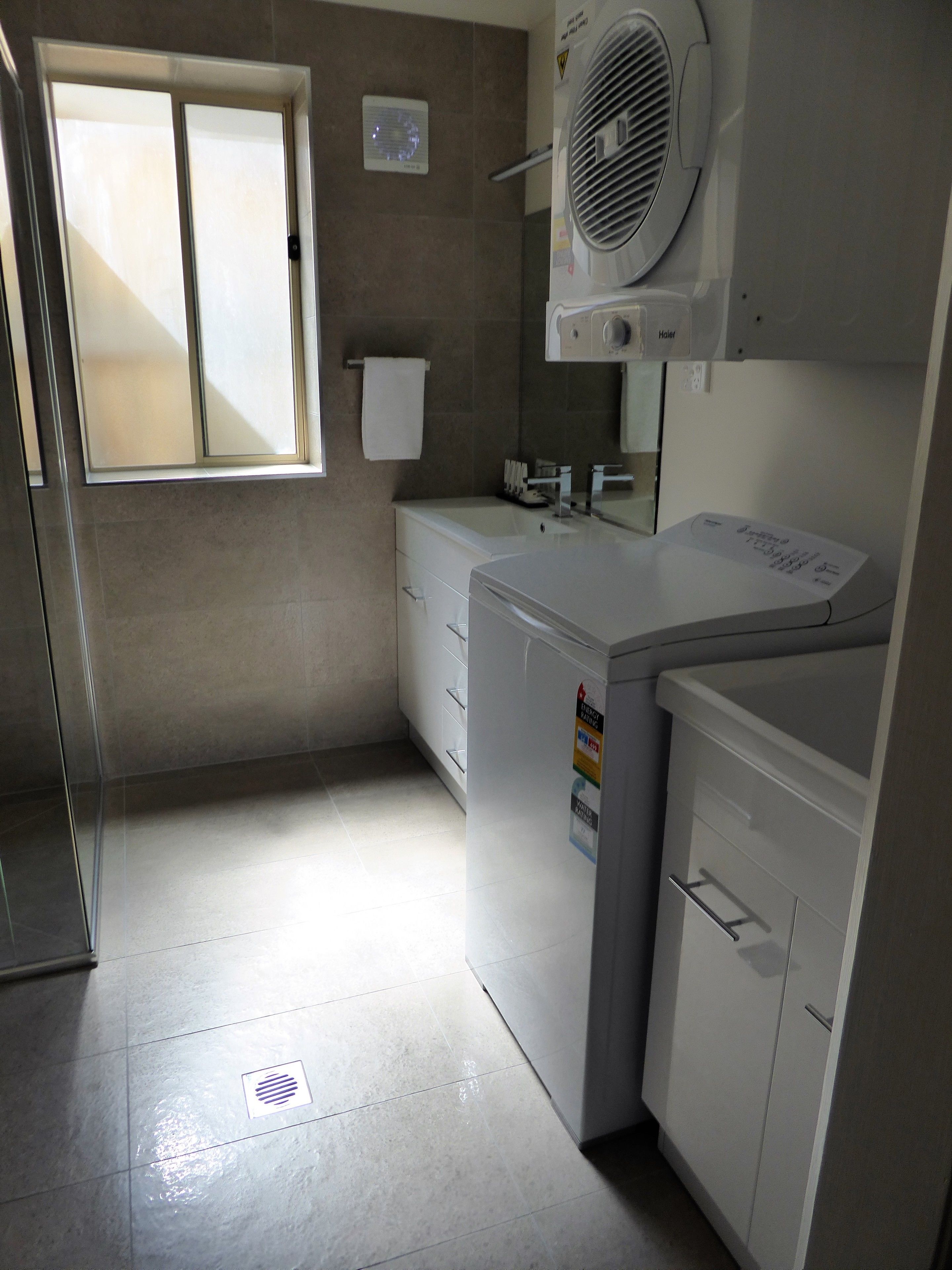 A compact laundry room with a washing machine, dryer, and a small window.