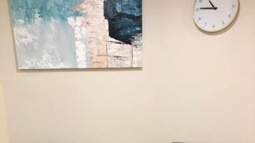 Dos sillones grises enfrentados, con una mesita redonda entre ellos, un reloj en la pared y un cuadro sobre la mesa.