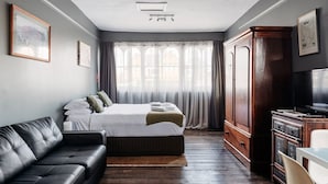 Un dormitorio con una cama, un sofá de cuero, un armario de madera y un televisor.