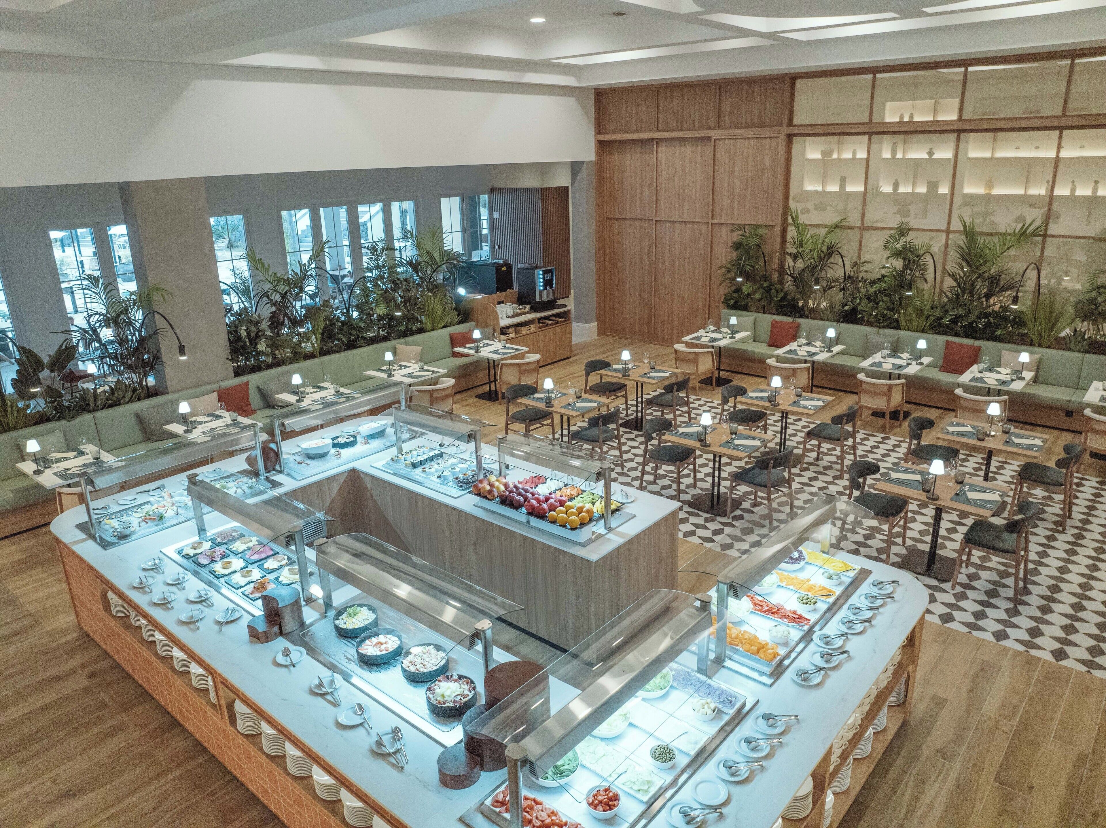 Un espace buffet proposant différents stands de nourriture et divers types de tables et de chaises.