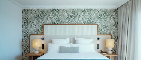 Een net opgemaakt bed met een houten hoofdbord, twee bedlampjes en behang met een patroon.