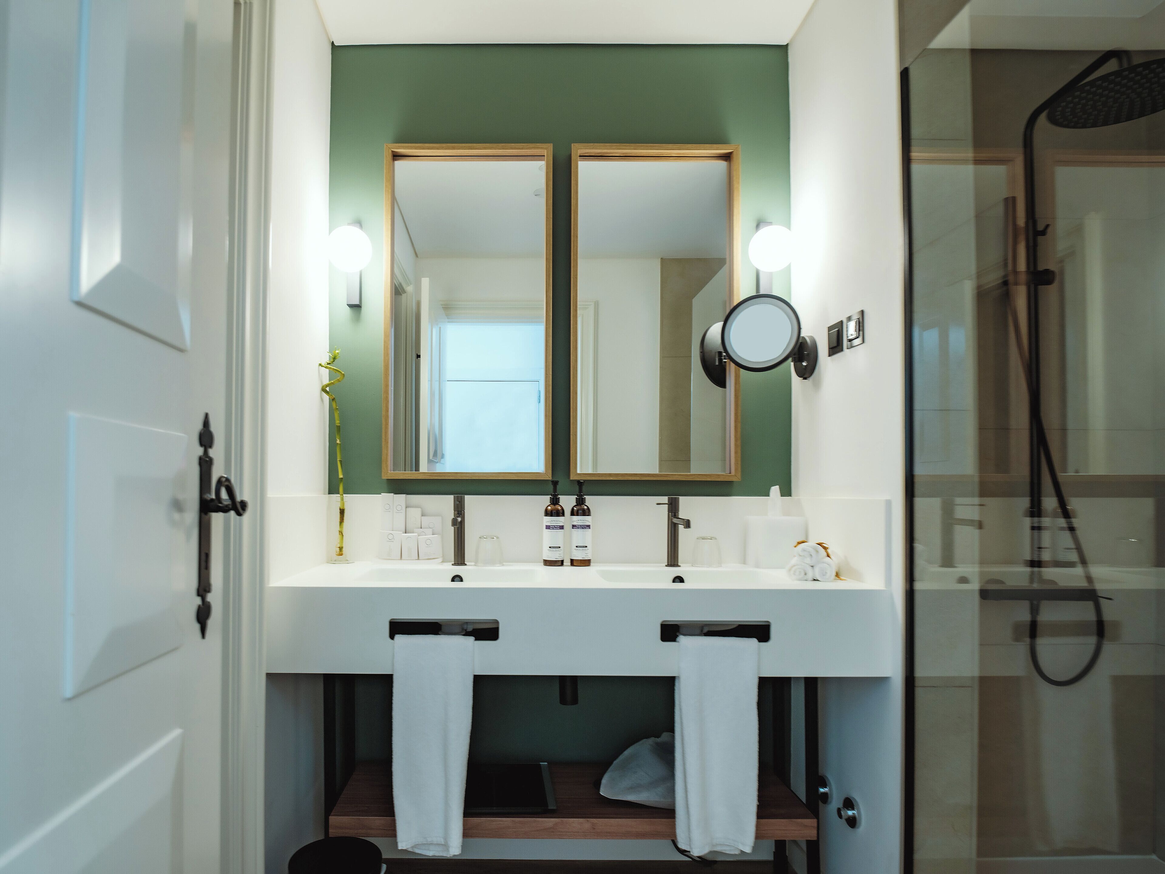 A bathroom with a double sink, a mirror, and a shower.