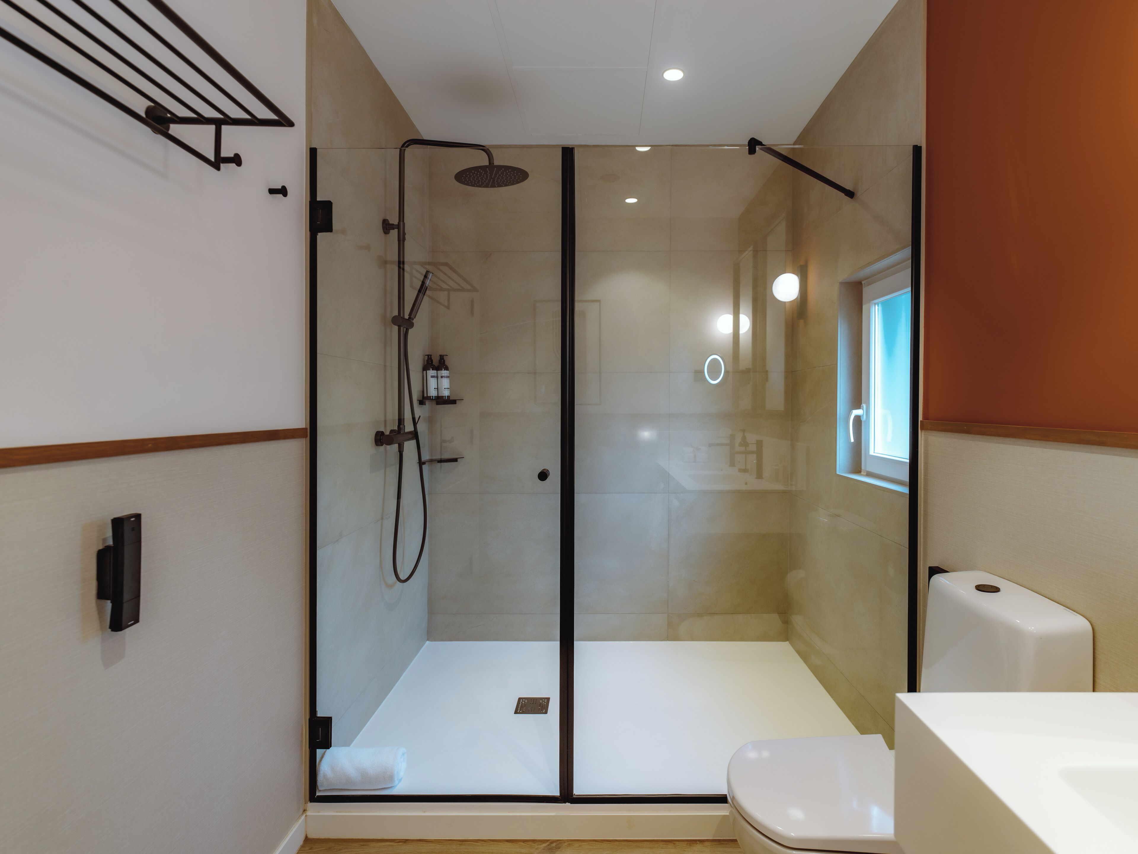 A modern bathroom with a glass-enclosed shower, a white toilet, and a visible sink area.