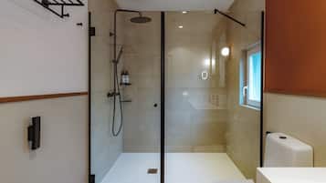 A modern bathroom with a glass-enclosed shower, a white toilet, and a visible sink area.