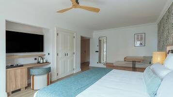 Une chambre d’hôtel moderne dotée d’un grand lit, d’un bureau avec un téléviseur à écran plat, d’un ventilateur de plafond et d’un miroir.