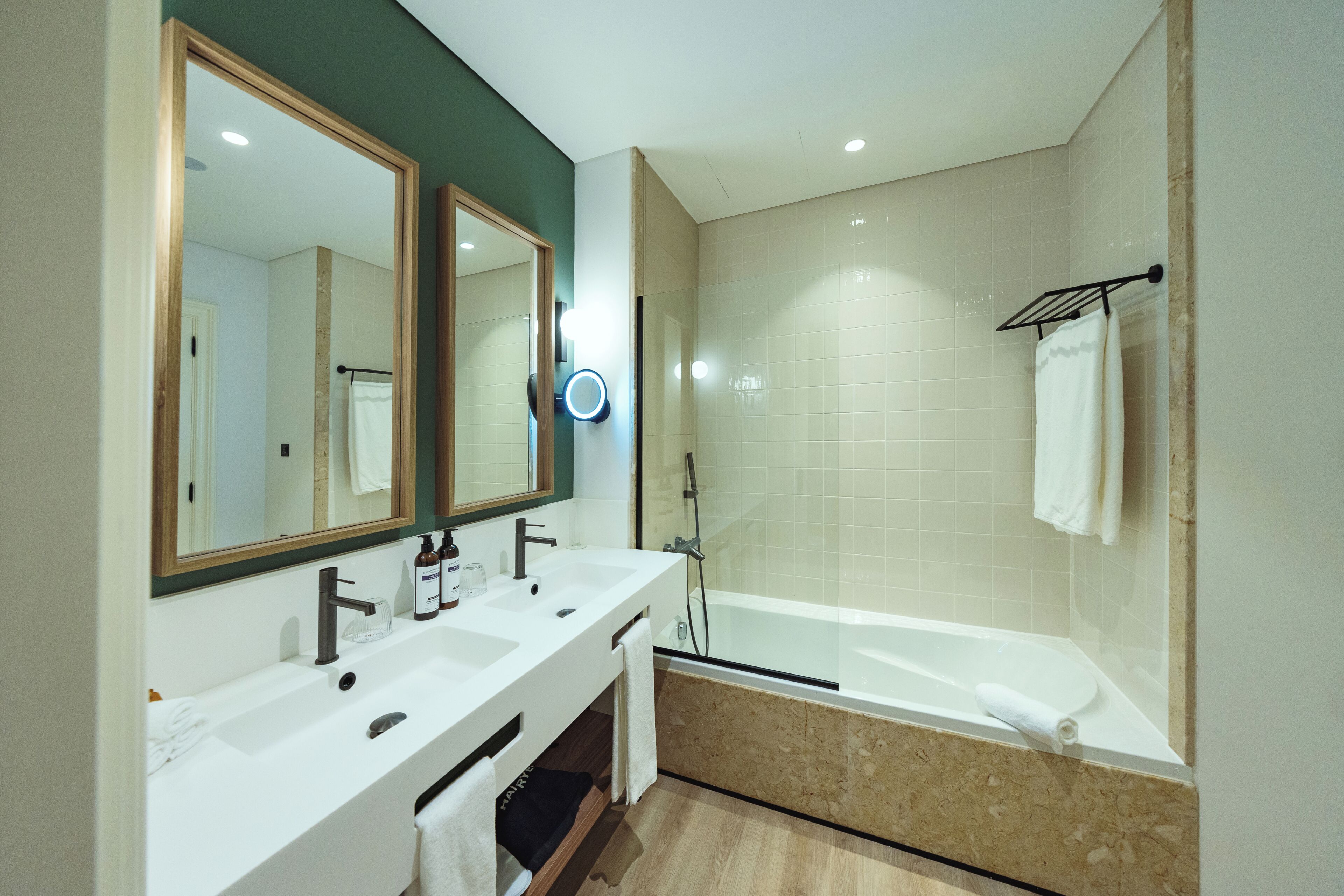 Un bagno moderno con un doppio lavabo, un grande specchio, un soffione doccia a mano e una vasca da bagno.