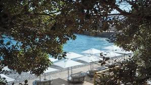A pool area with umbrellas and lounge chairs, surrounded by trees. - Hyatt Ziva Madeira (Machico)