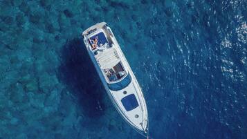 Vista aérea de un barco en aguas turquesas cristalinas.