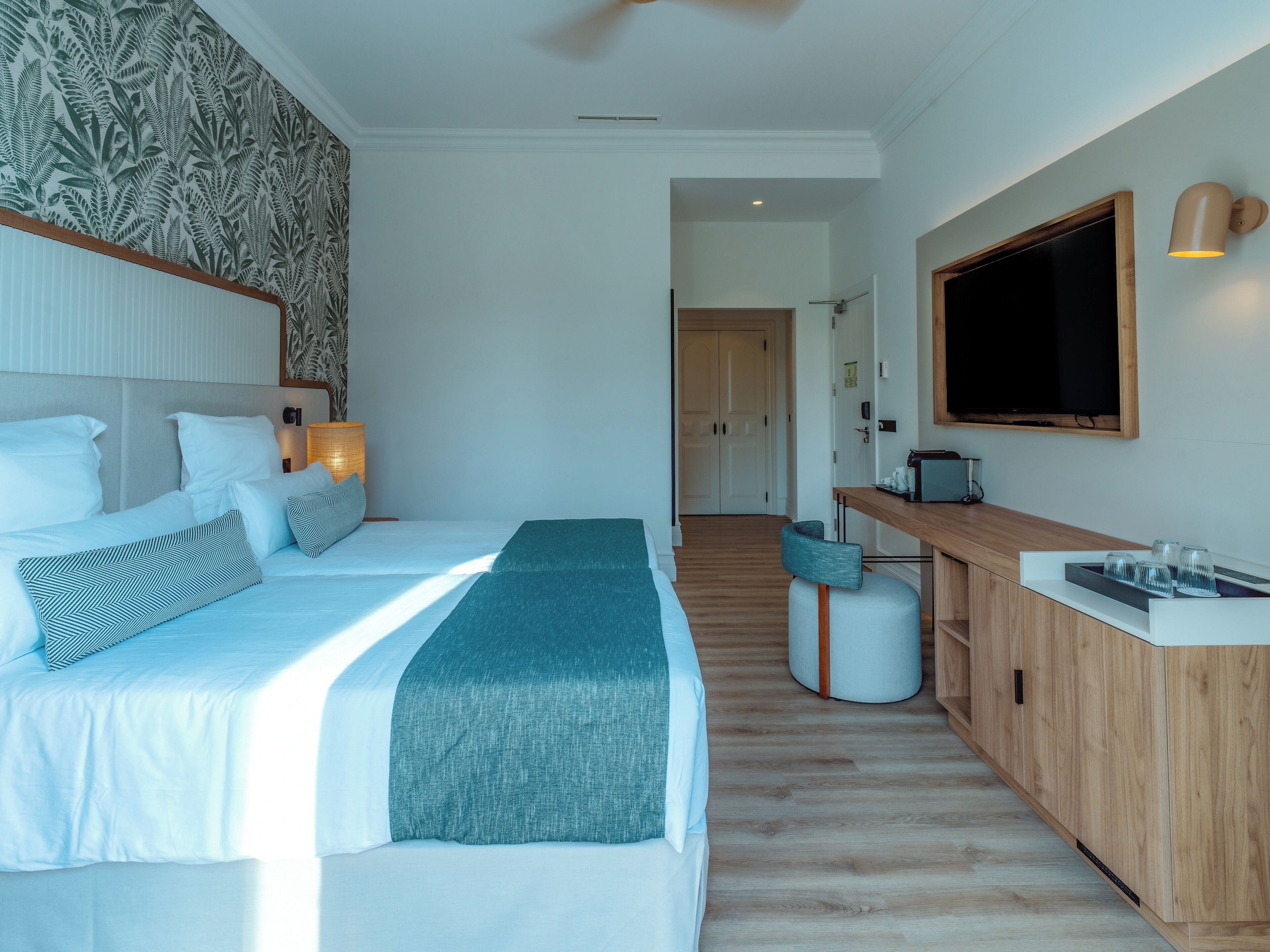 Une chambre d’hôtel moderne, dotée d’un grand lit, d’un bureau et d’une télévision.