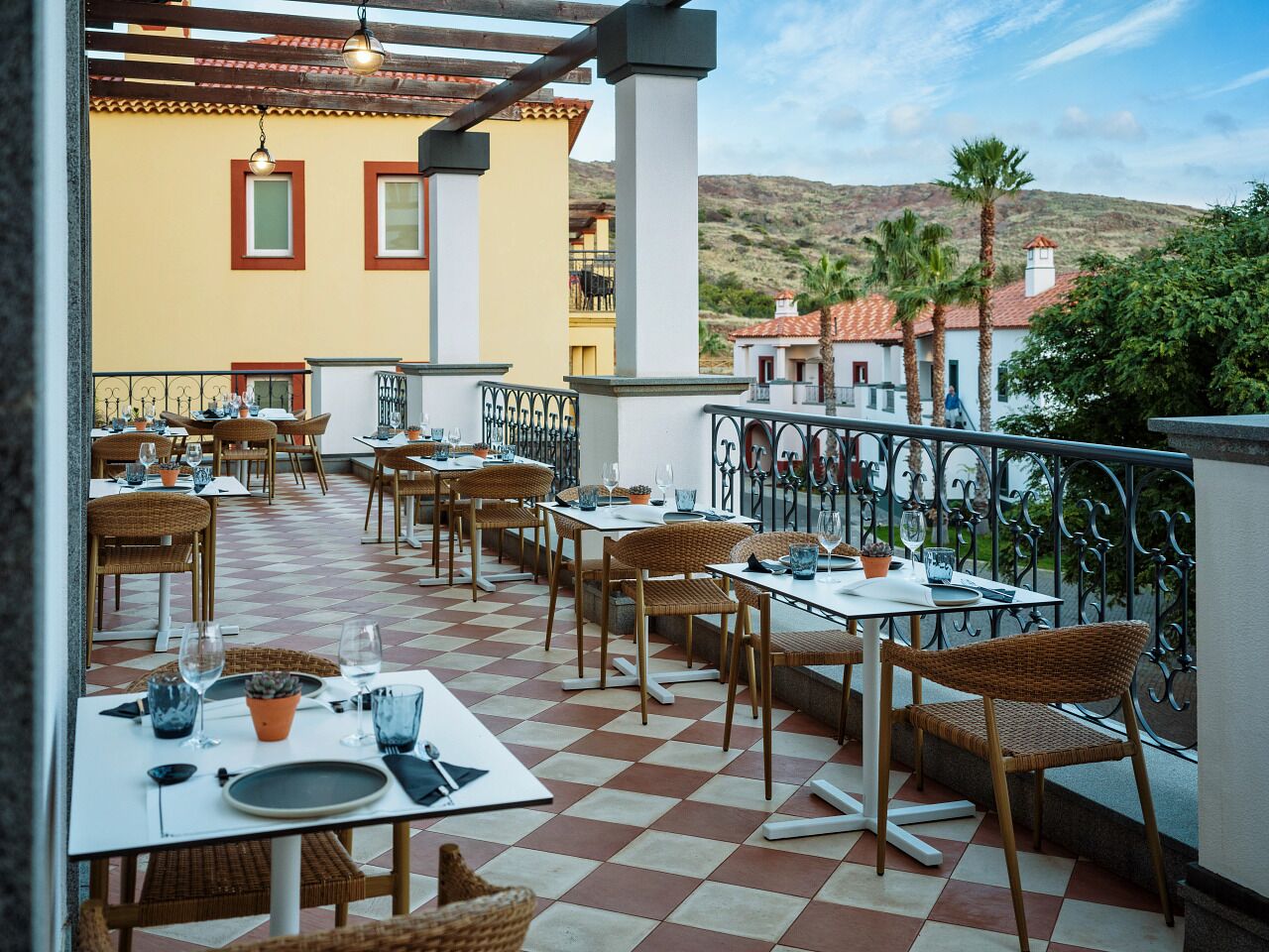 Un espace de restauration en plein air avec des tables et des chaises, un sol à carreaux et une vue sur le paysage environnant.