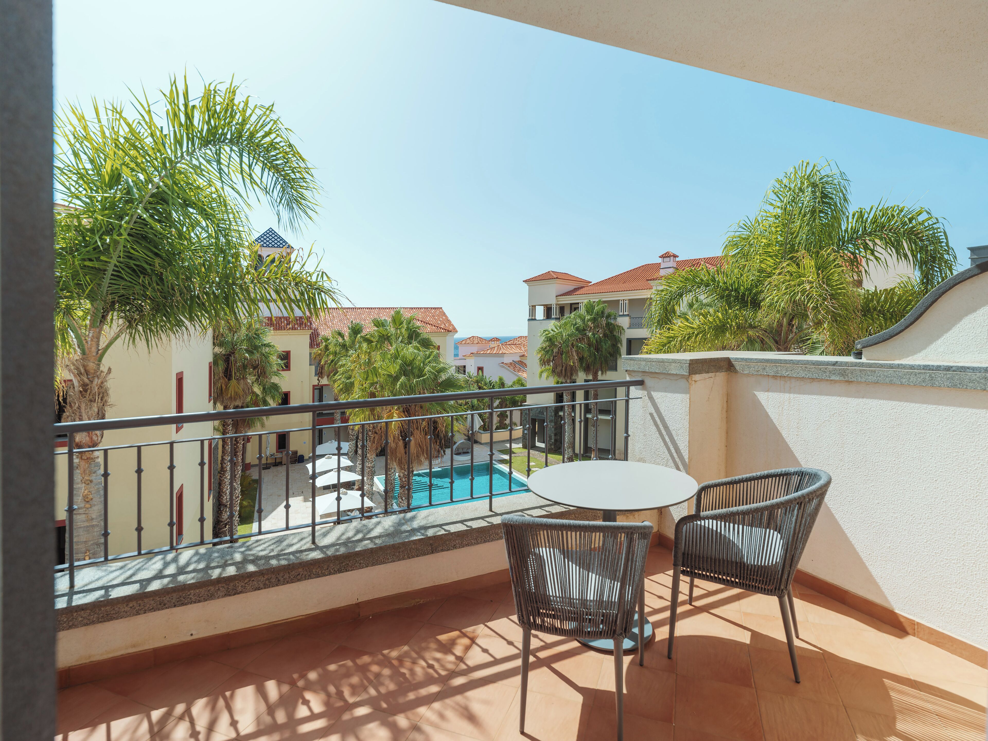 A balcony with a pool, outdoor furniture, and surrounding buildings.