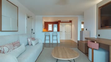 A modern living room with a sofa, a coffee table, and a kitchen area in the background.