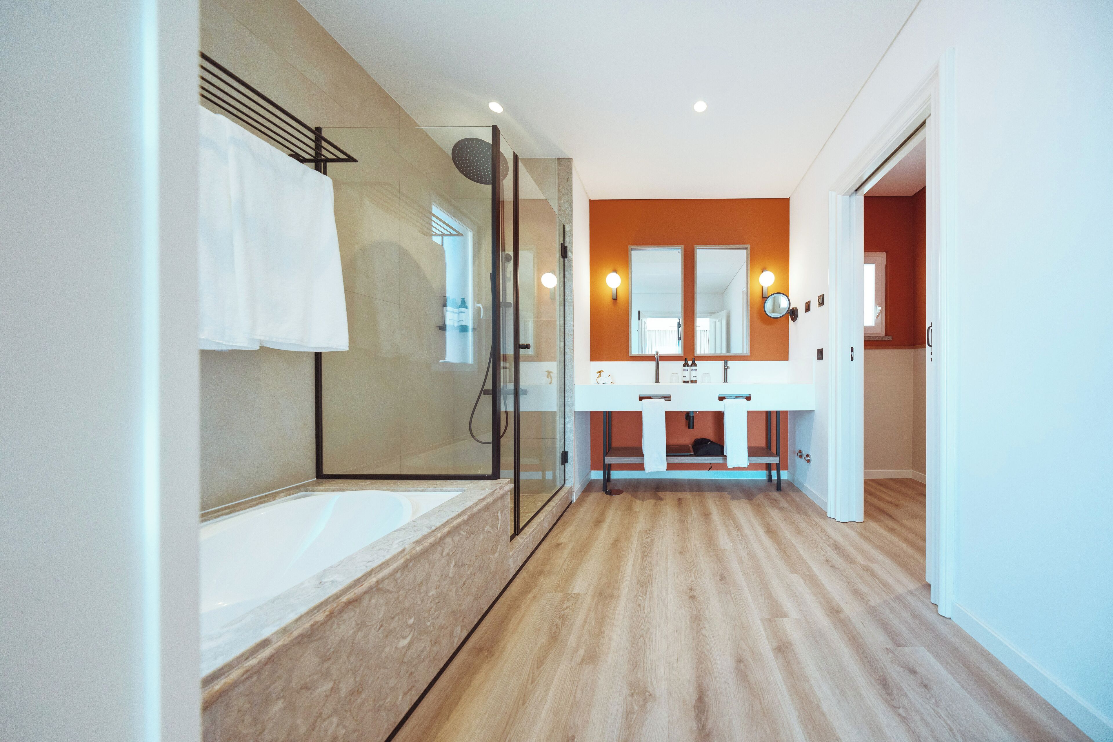 Une salle de bain moderne avec une douche à parois de verre, un grand miroir et un plancher en bois.