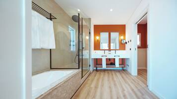 Une salle de bain moderne avec une douche à parois de verre, un grand miroir et un plancher en bois.