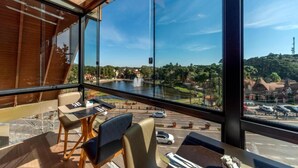 A modern room with large windows overlooking a cityscape and a river. - Hotel Laghetto Gramado (Gramado)