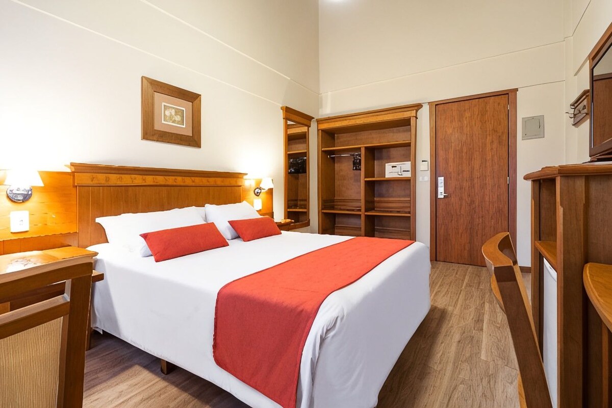 A hotel room with a bed, bedside tables, a wardrobe, and a mirror.