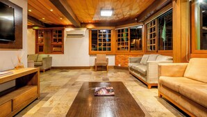 A spacious living room with a wooden coffee table, a sofa, and a television mounted on the wall. - Hotel Laghetto Gramado (Gramado)