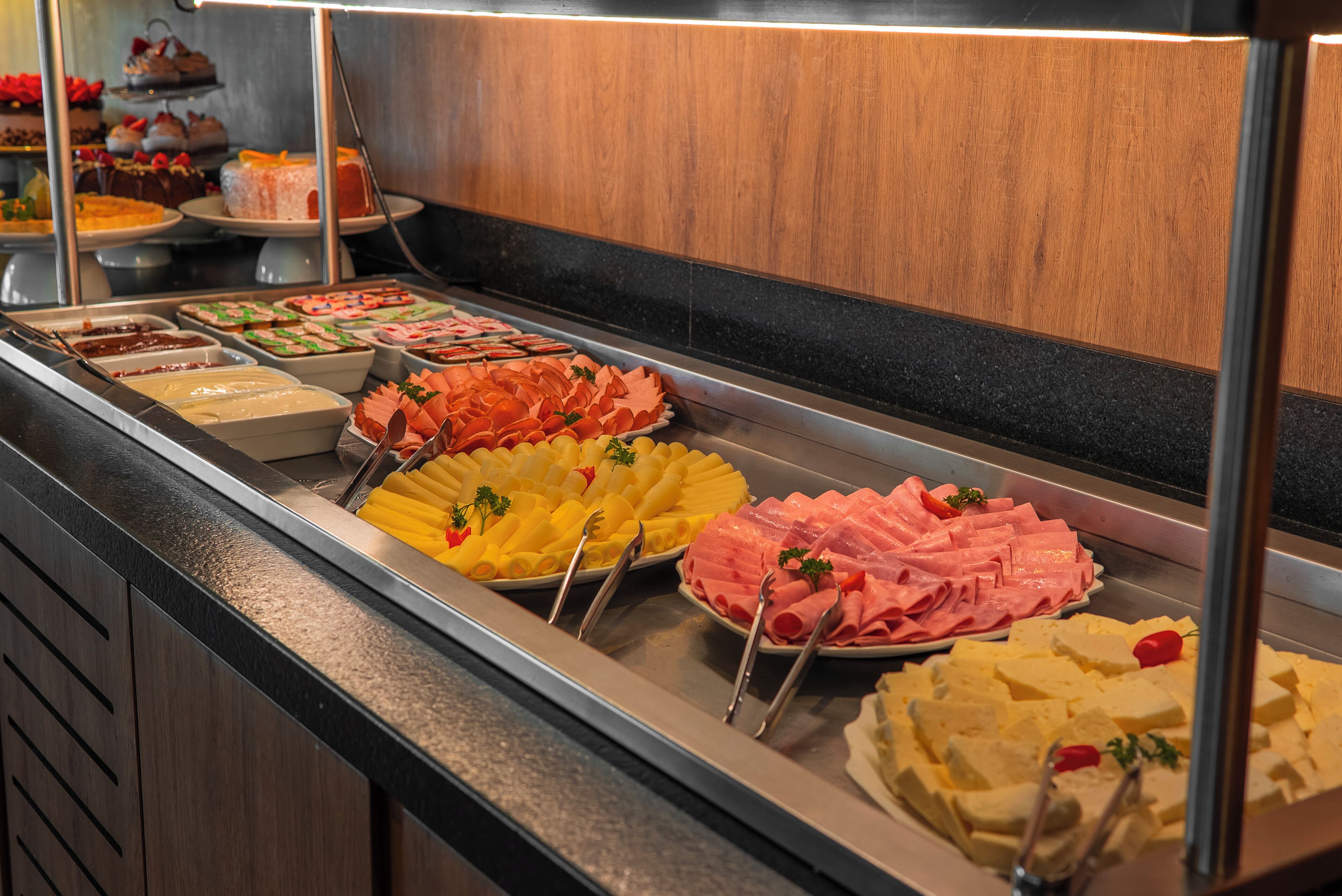 A buffet with various food items including meats, cheeses, and fruits.
