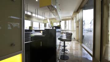 Un intérieur moderne avec un bar, des espaces pour s’asseoir et de grandes fenêtres.