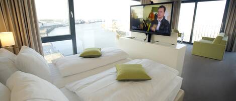 A hotel room with a bed, a television, and a view of a body of water.
