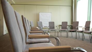 Un salón de conferencias con filas de sillas mirando hacia una pizarra.