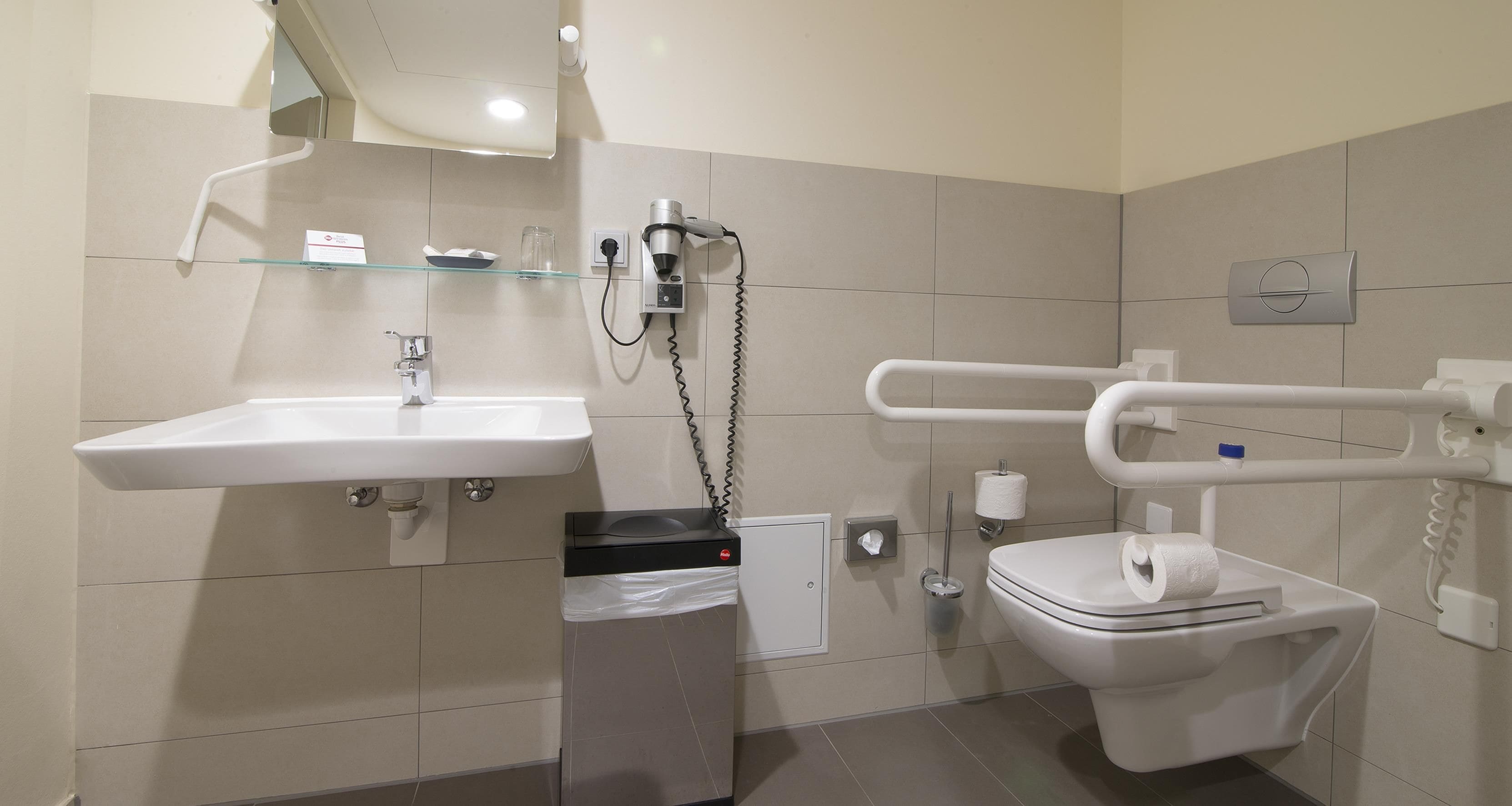 Un baño moderno con lavamanos, inodoro y secamanos.