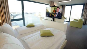 A hotel room with two beds, a television, and a view of a river. - Best Western Plus Hotel Bremerhaven (Bremerhaven)