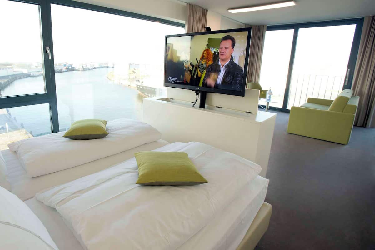 A hotel room with two beds, a television, and a view of a river.