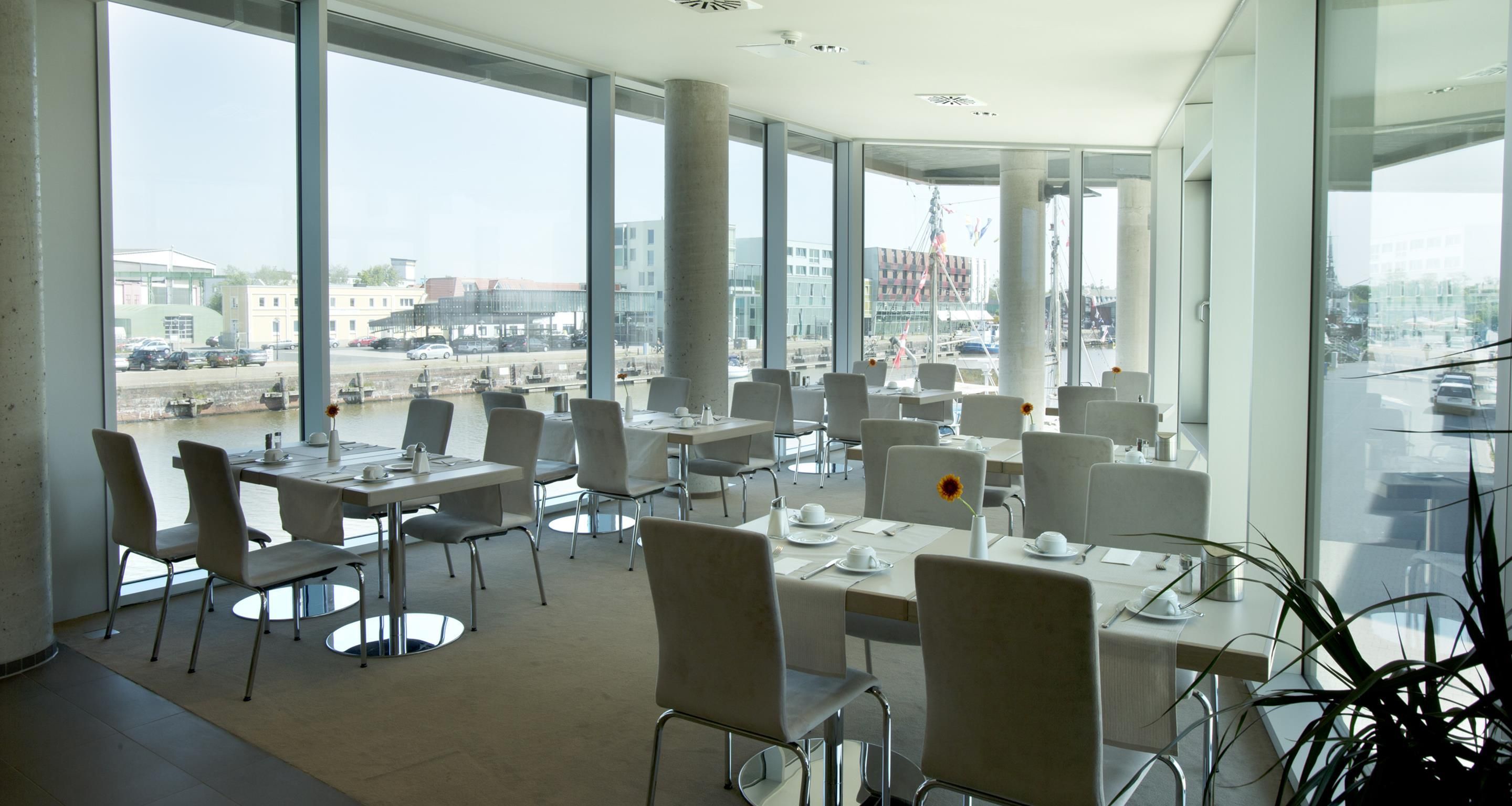 Un comedor moderno con mesas y sillas, ventanas amplias y vistas a la ciudad.