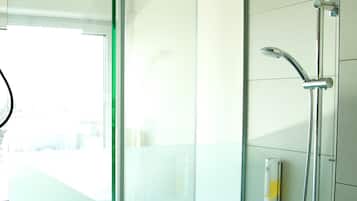 A modern bathroom with a glass shower enclosure, a towel rack, and a visible bottle of shampoo.