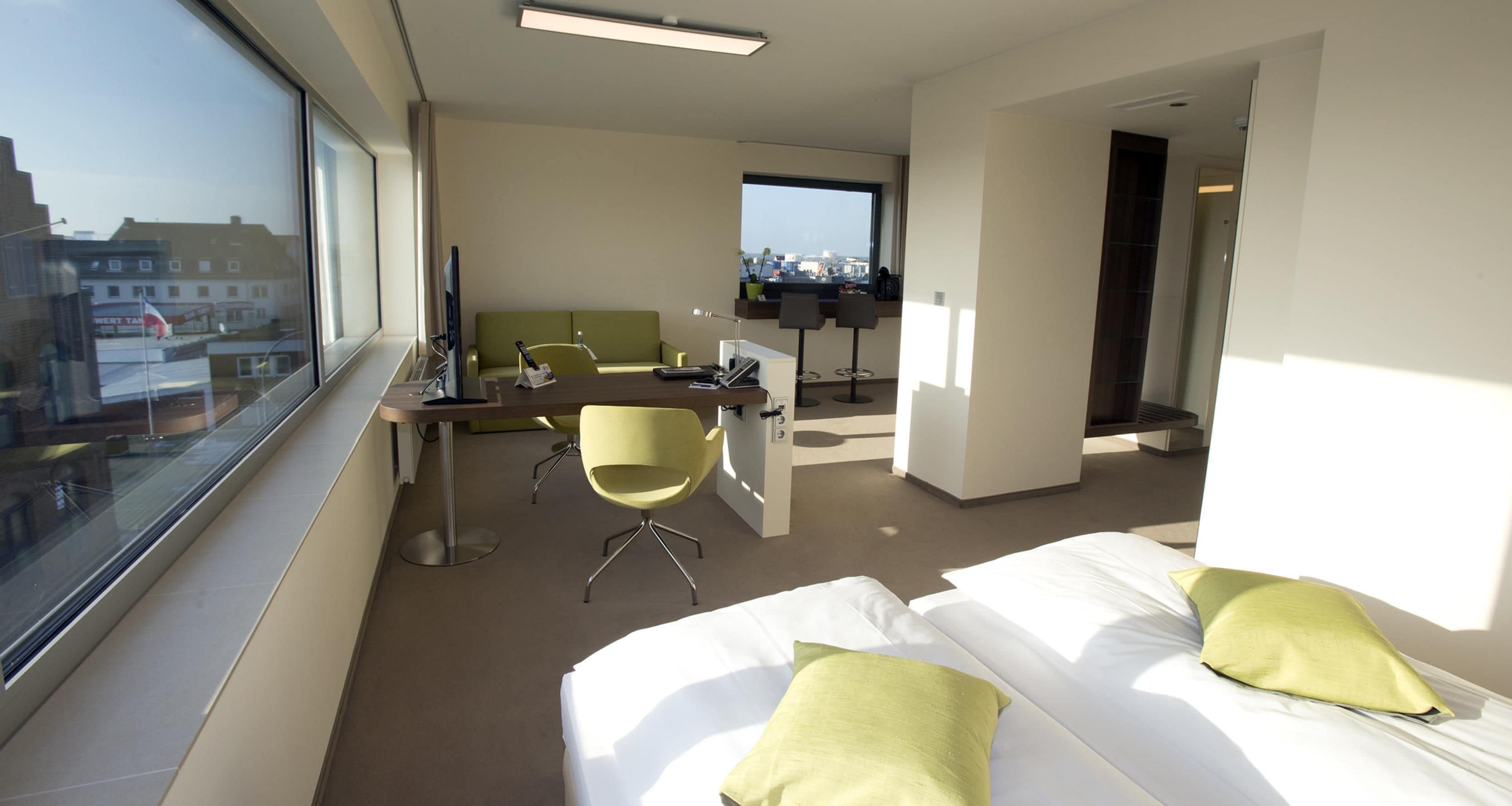 Ein Hotelzimmer mit einem Bett, einem Schreibtisch, einem Stuhl und einem großen Fenster.