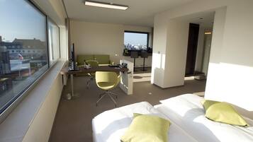 Ein Hotelzimmer mit einem Bett, einem Schreibtisch, einem Stuhl und einem großen Fenster.