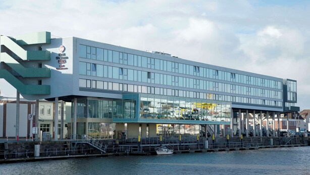 A modern building with a glass facade, multiple floors, and a waterfront location. - Best Western Plus Hotel Bremerhaven (Bremerhaven)