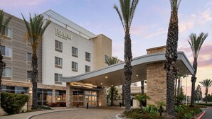Ein Fairfield by Marriott Hotel mit modernem Design, inklusive überdachter Eingangsbereiches und Palmen.