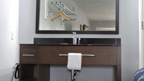 A bathroom with a large mirror, a towel rack, a sink, and a cabinet. - Riata Inn Crystal City (Crystal City)