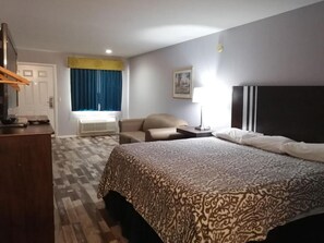 A hotel room with a bed, a desk, a chair, and a window with curtains.