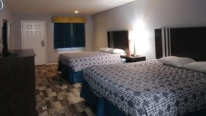 A hotel room with two beds, a desk, a chair, a TV, and a window with curtains. - Riata Inn Crystal City (Crystal City)