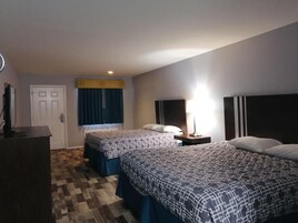 Habitación de hotel con dos camas, un escritorio, una silla, un televisor y una ventana con cortinas.