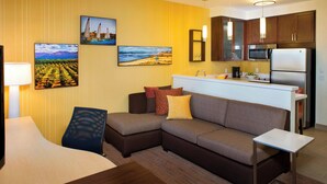 A modern hotel room with a sectional sofa, a small table, and a kitchenette. - Residence Inn Tustin Orange County (Tustin)