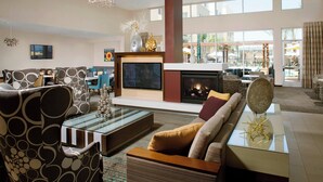 A modern living room with a fireplace, comfortable seating, and a large window offering a view of the outdoors. - Residence Inn Tustin Orange County (Tustin)