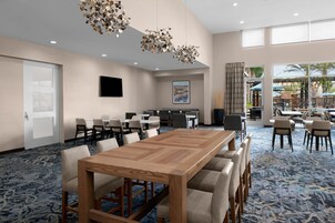 A conference room with a large wooden table, multiple chairs, and a carpeted floor.