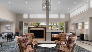A spacious lobby with a fireplace, comfortable seating, and large windows offering views of the outdoors.