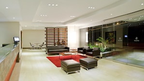 A modern hotel lobby with a reception desk, seating area, and a glass wall. - Hotel Estelar Calle 100 (Bogotá)