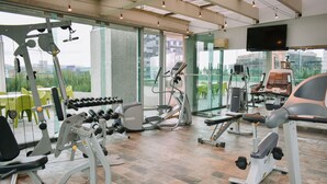 A gym with various exercise equipment, large windows, and a television on the wall. - Hotel Estelar Calle 100 (Bogotá)