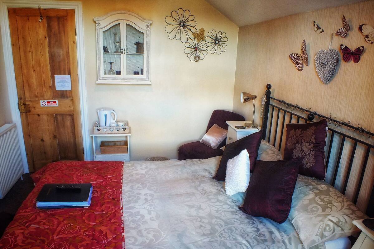 A bedroom with a bed, a nightstand, a dresser, a window, and wall decorations.