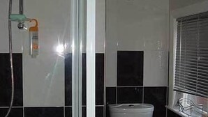 A bathroom with a shower, toilet, and window. - Heathfield B&B Guest House (Whitby)